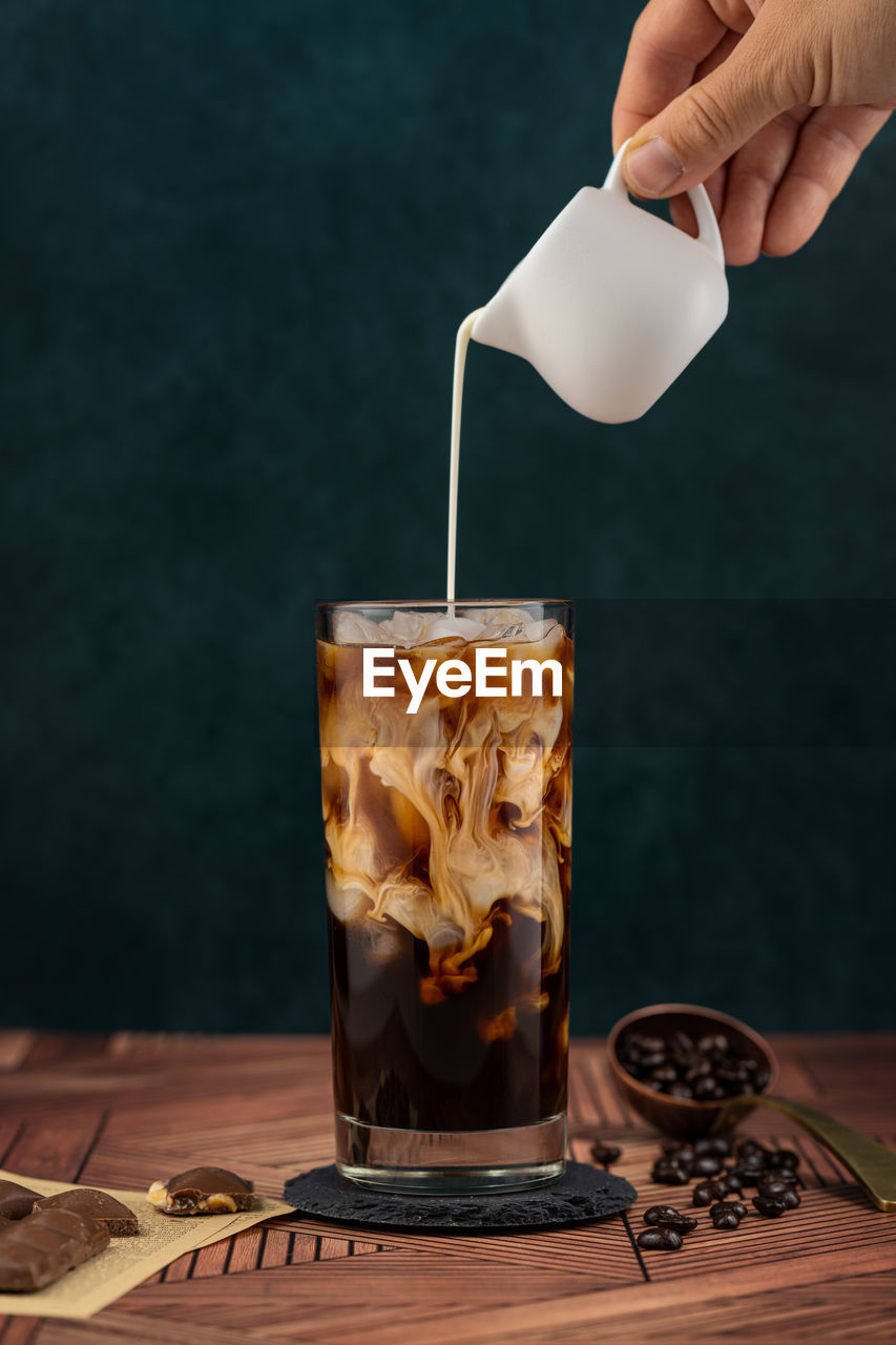 MIDSECTION OF PERSON POURING COFFEE IN CUP