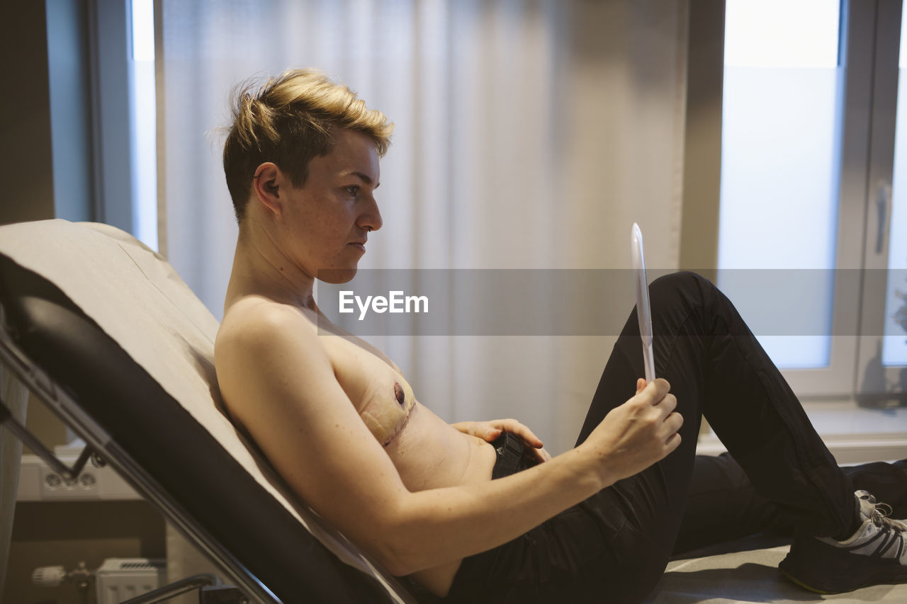 Patient after top surgery looking in mirror