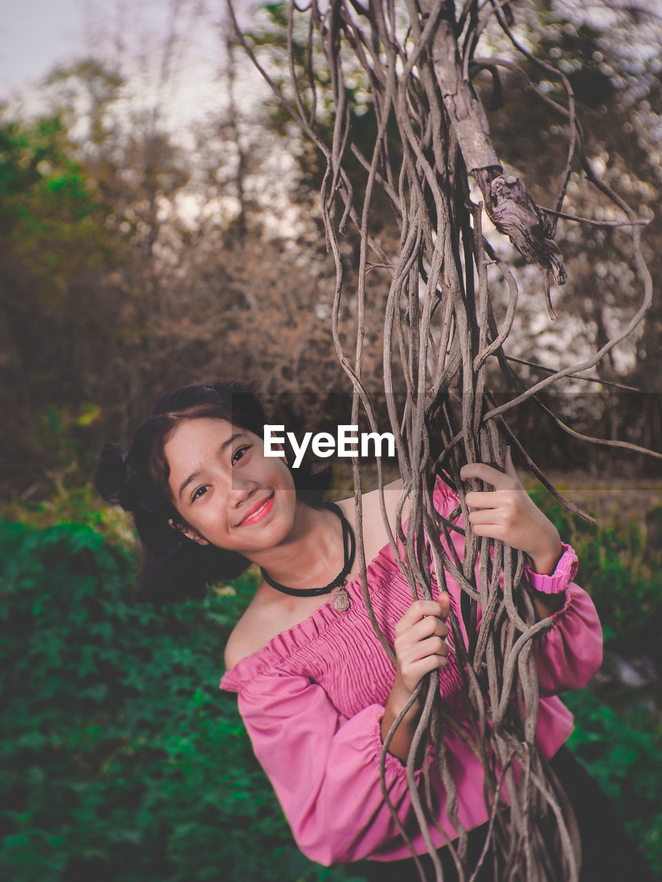 Portrait of smiling girl while holding vines of tree