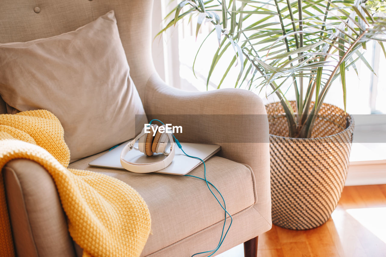 Headphones lying on laptop on armchair. cute minimalist room interior apartment decoration 