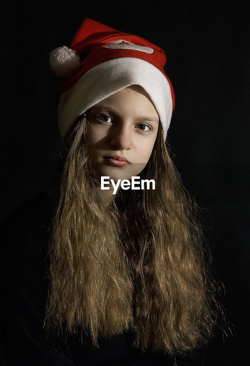 Portrait of girl in santa hat against black background