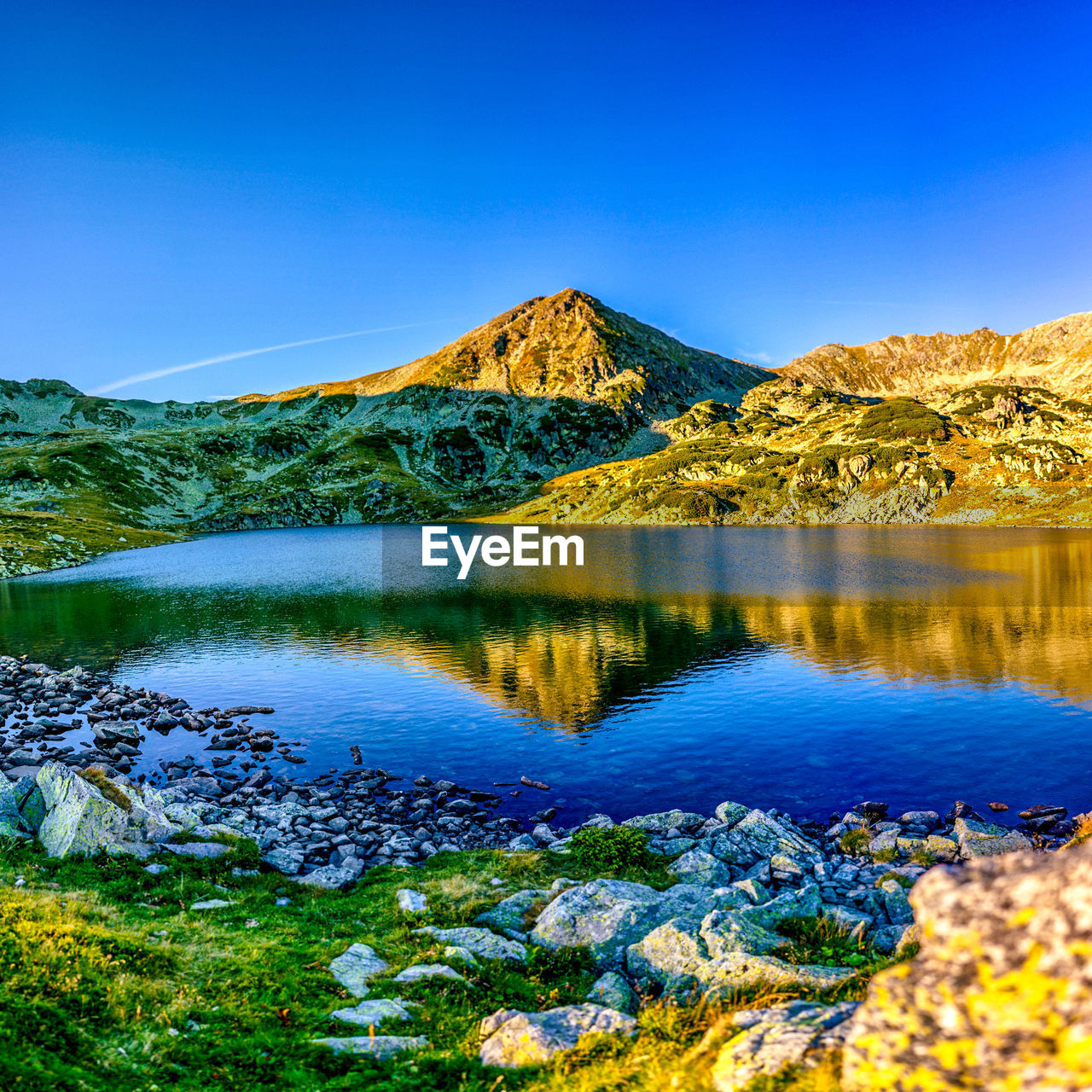 Scenic view of lake and mountains against clear blue sky
