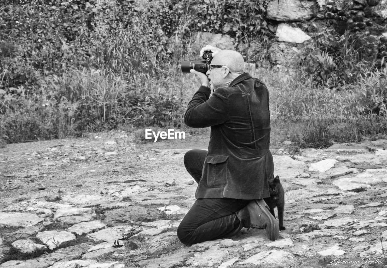 Man photographing with camera on land against plants
