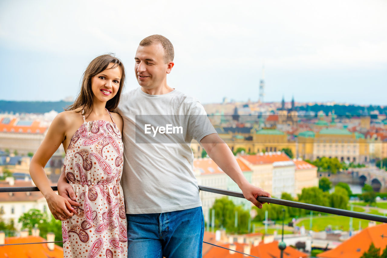 Portrait of happy woman standing with boyfriend against cityscape