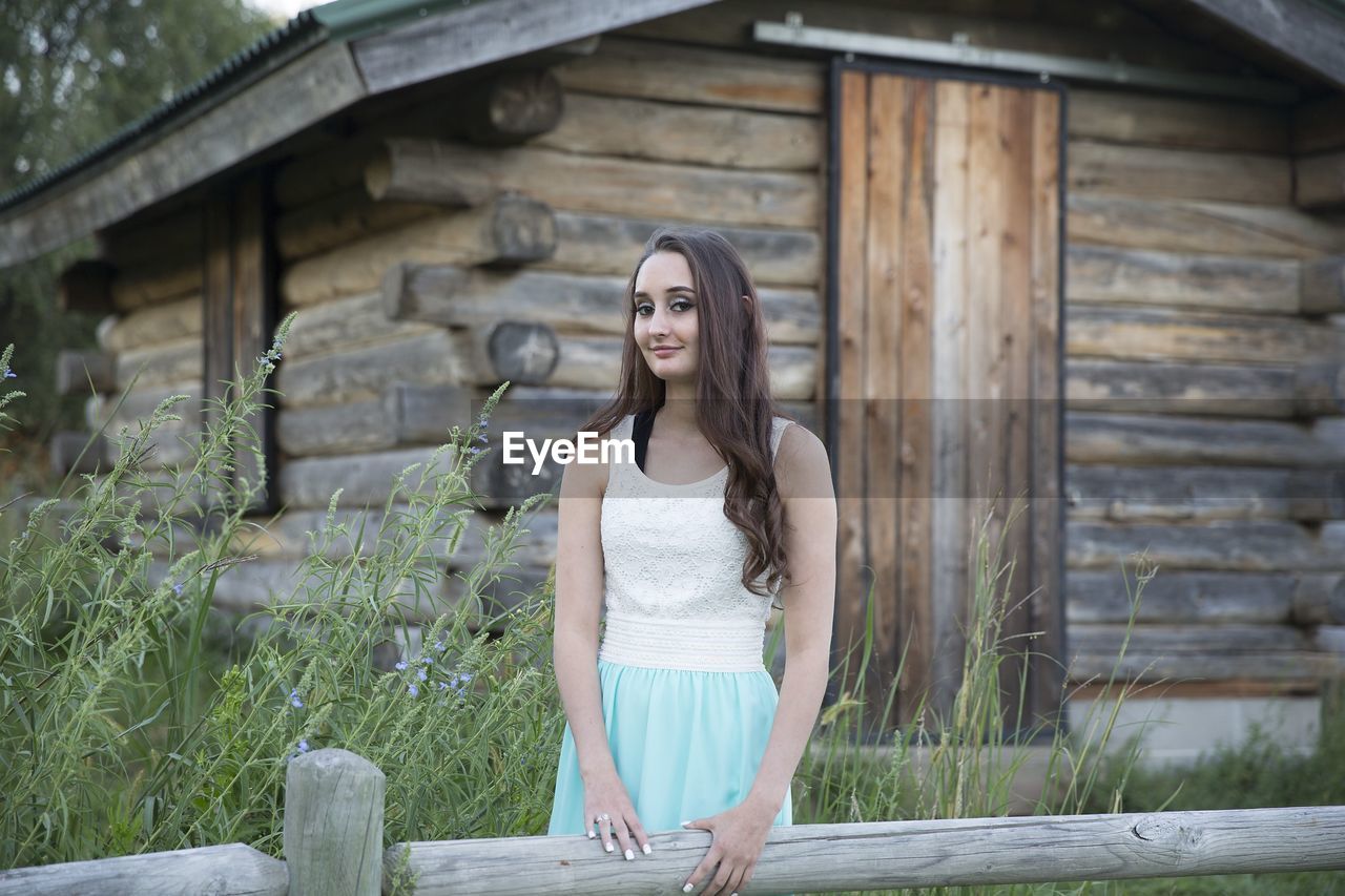 Portrait of young woman standing against wall