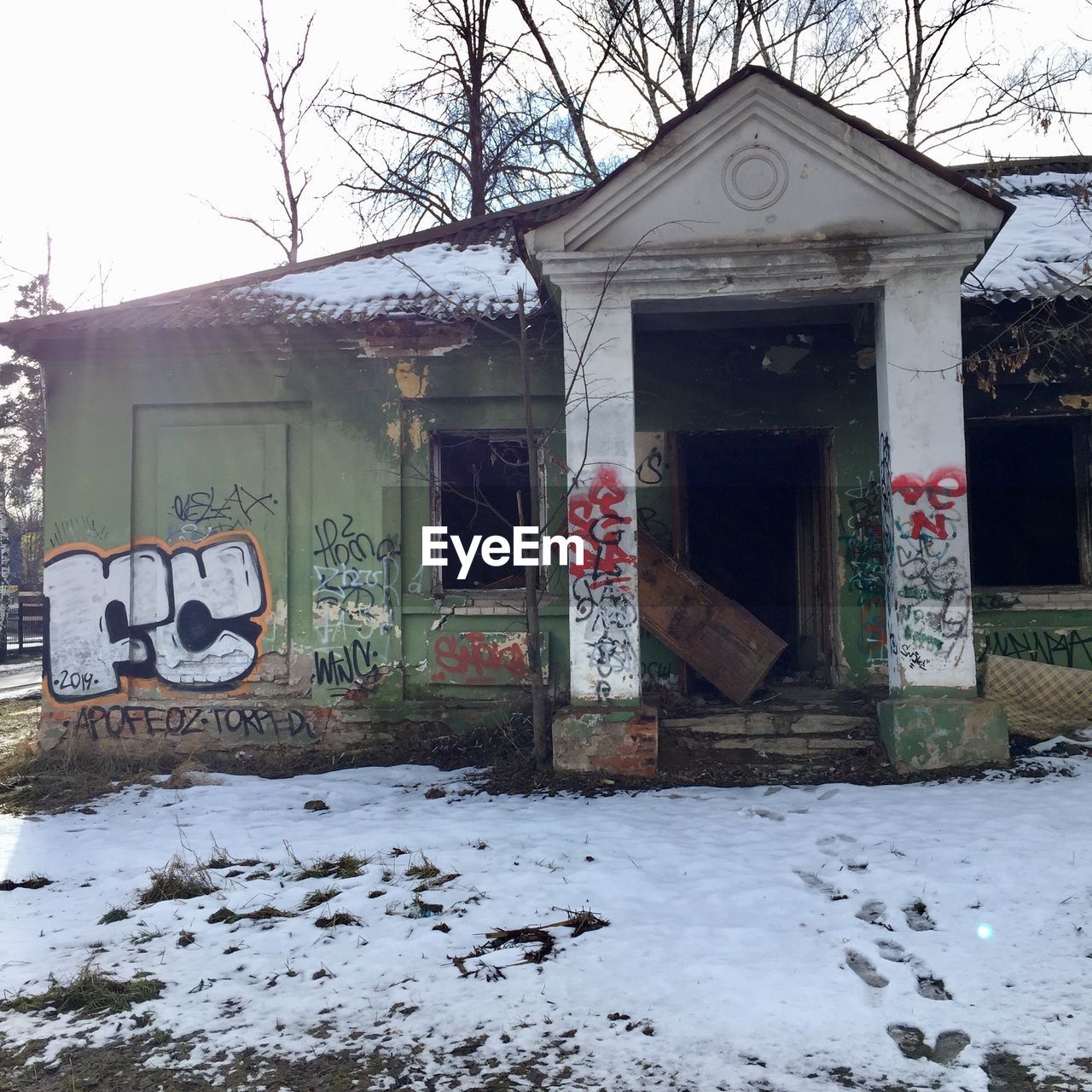 GRAFFITI ON HOUSE BY SNOW COVERED BUILDING