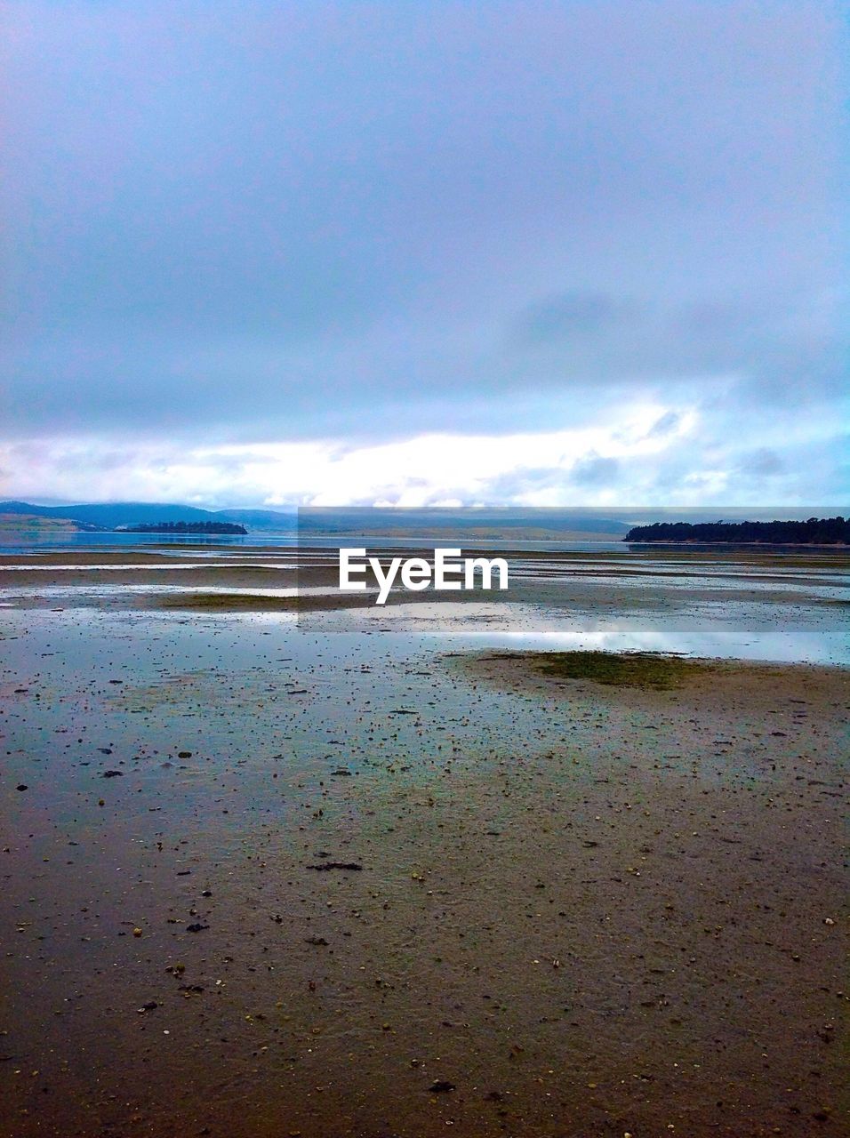 TRANQUIL VIEW OF BEACH AGAINST CLOUDY SKY