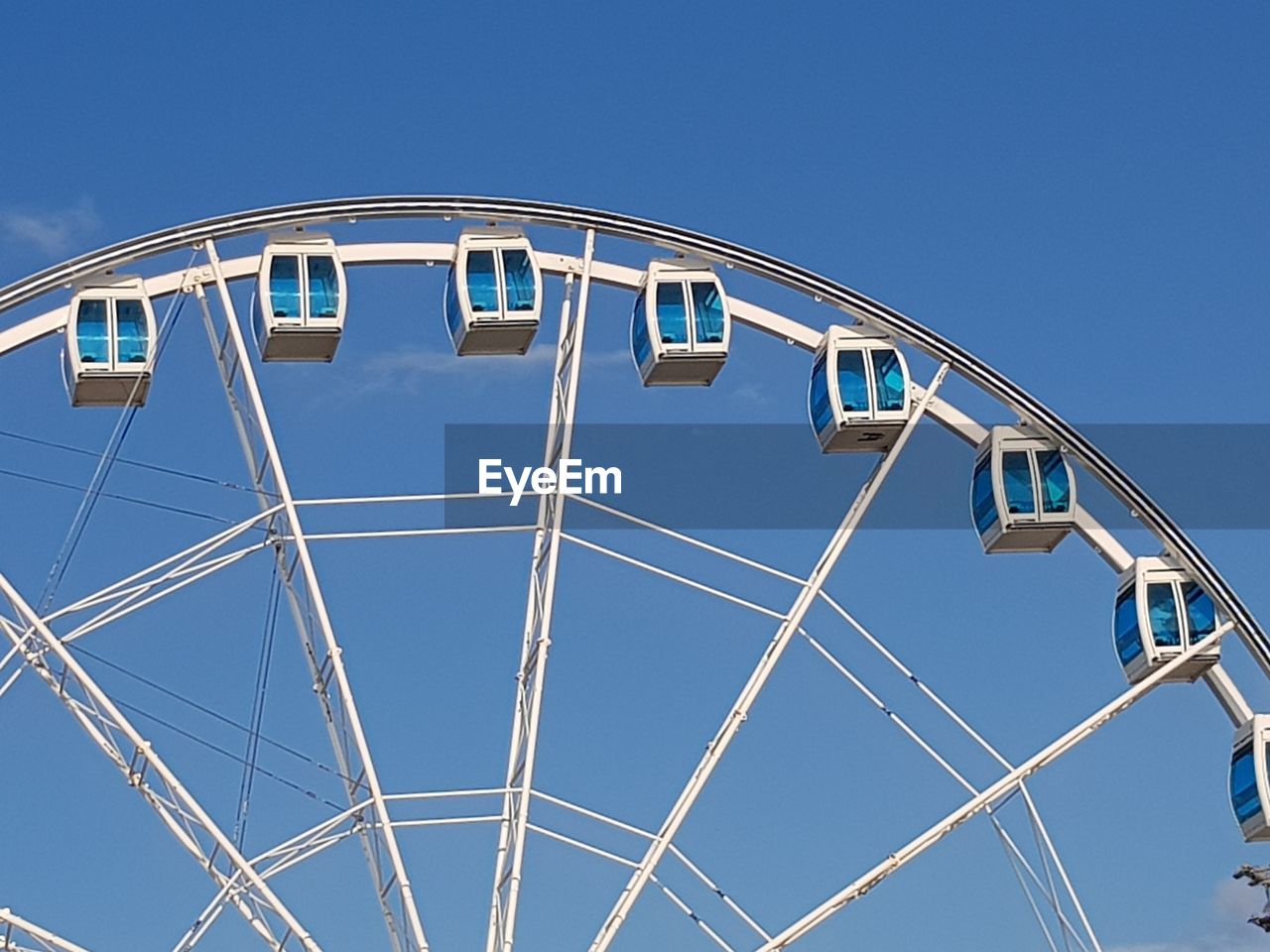 Low angle view of ferris wheel against clear blue sky