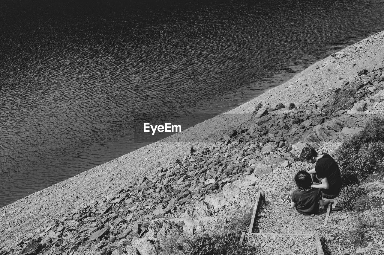 High angle view of brothers sitting by water