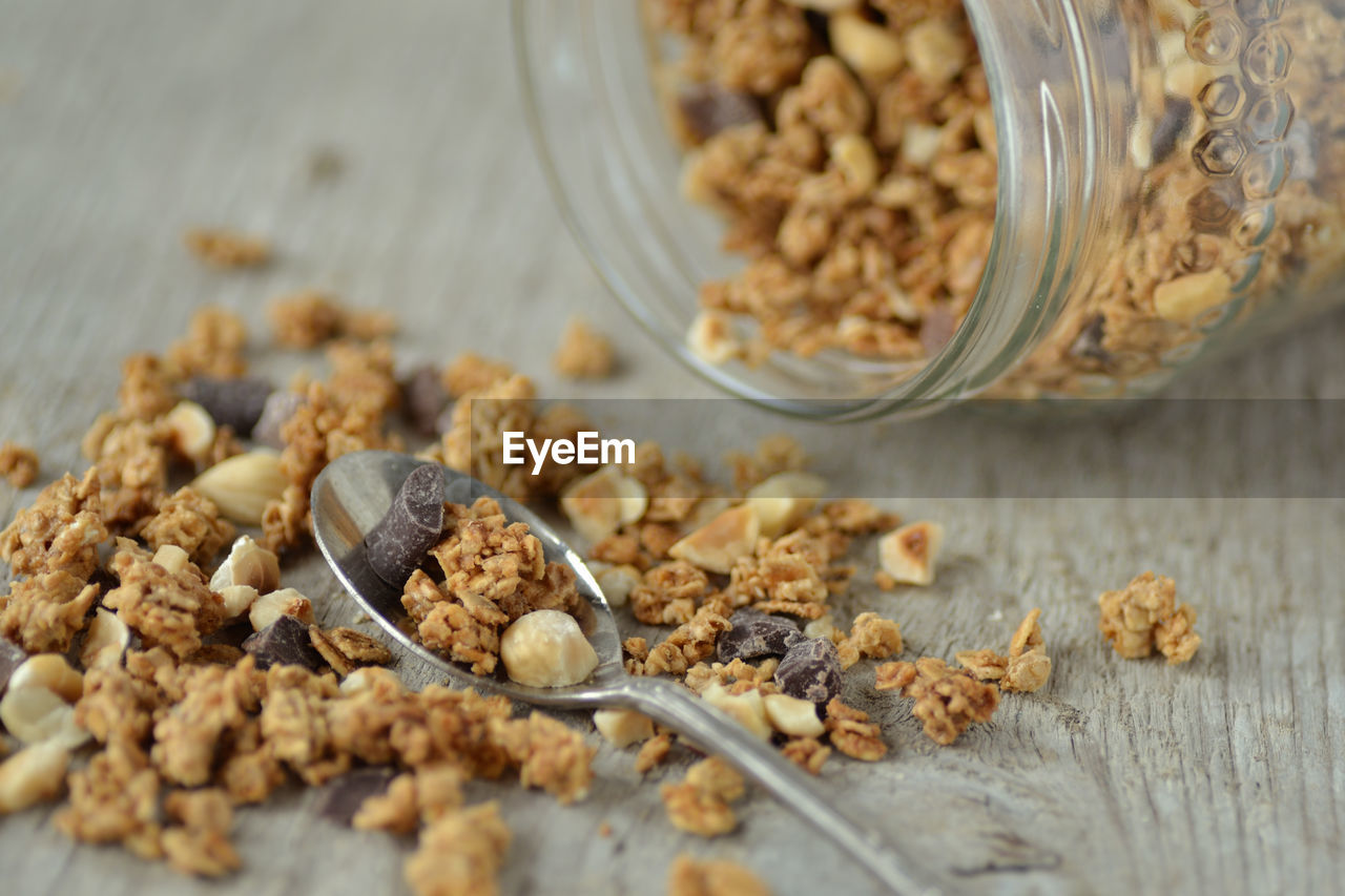Close-up of granola in spoon by glass jar on table