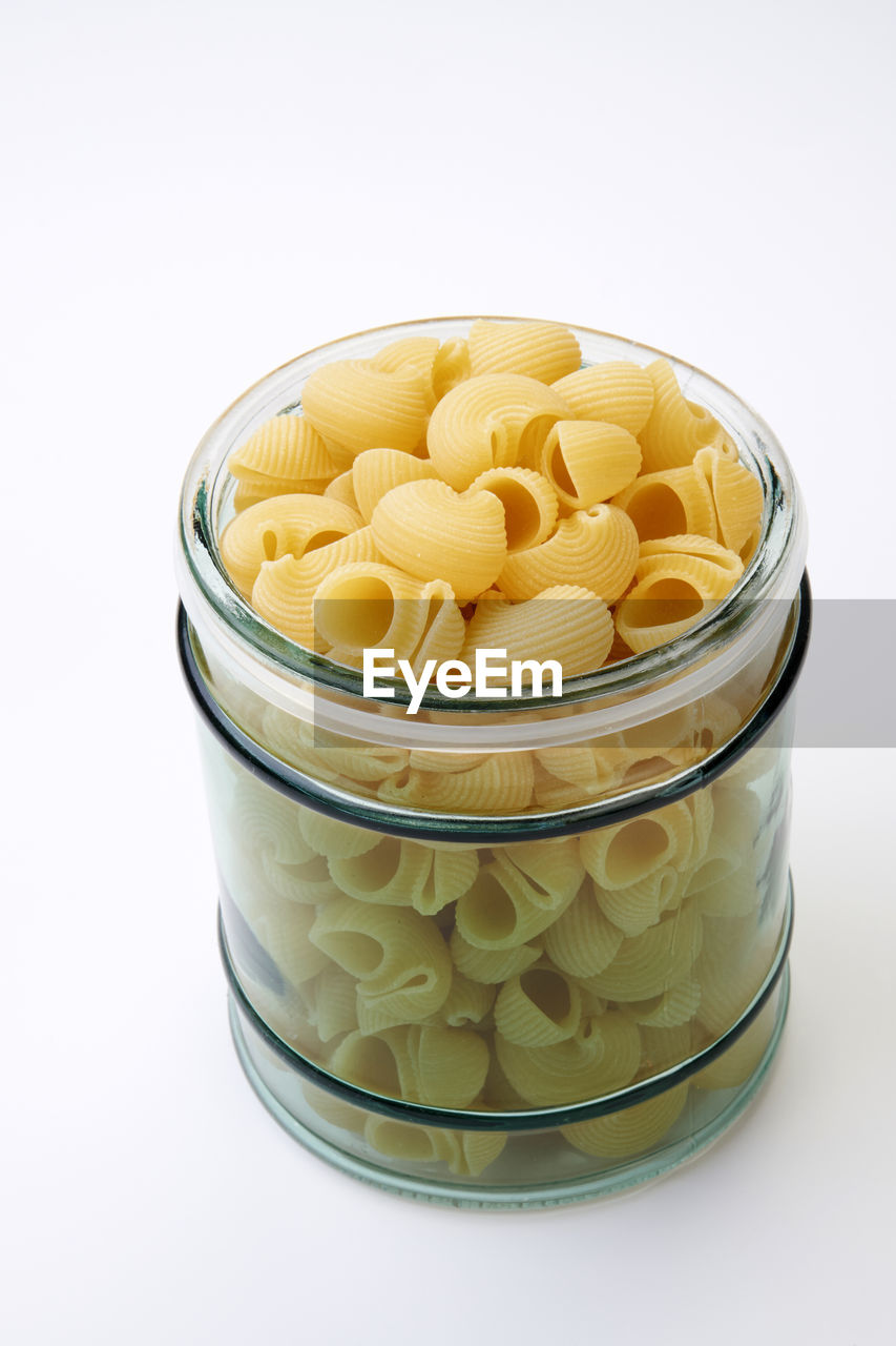 Close-up of pasta in jar over white background