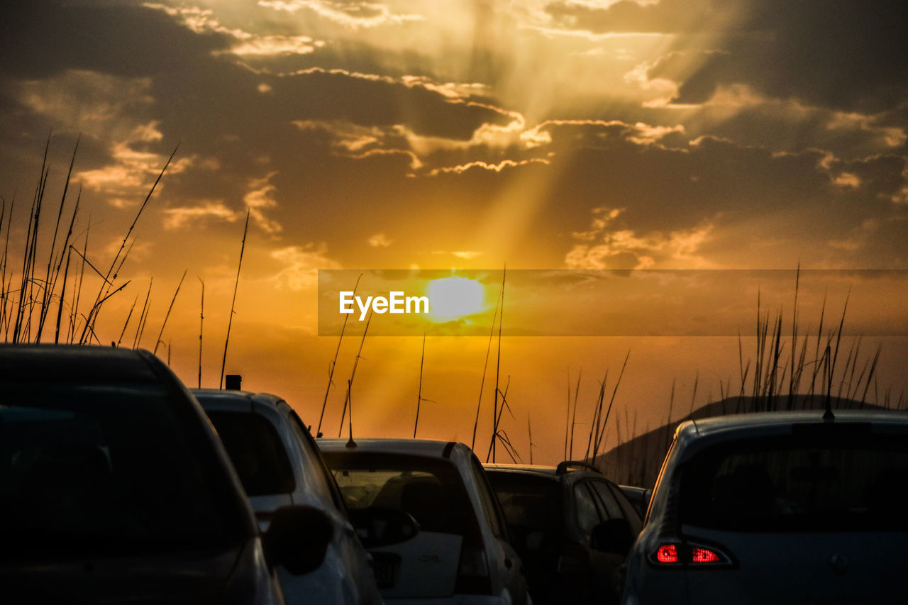 CLOSE-UP OF CARS AGAINST ORANGE SKY