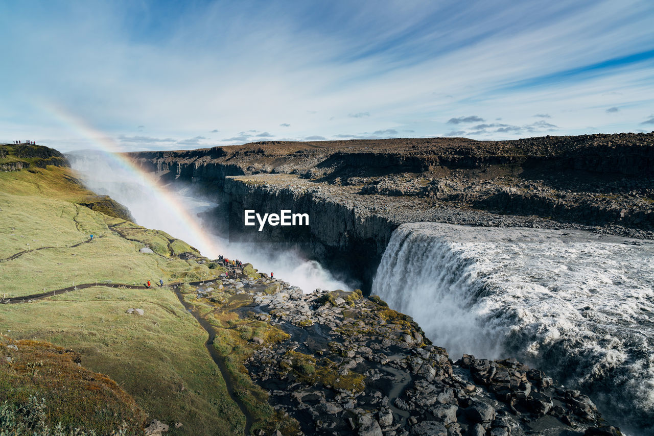 Scenic view of rainbow over waterfall in crater