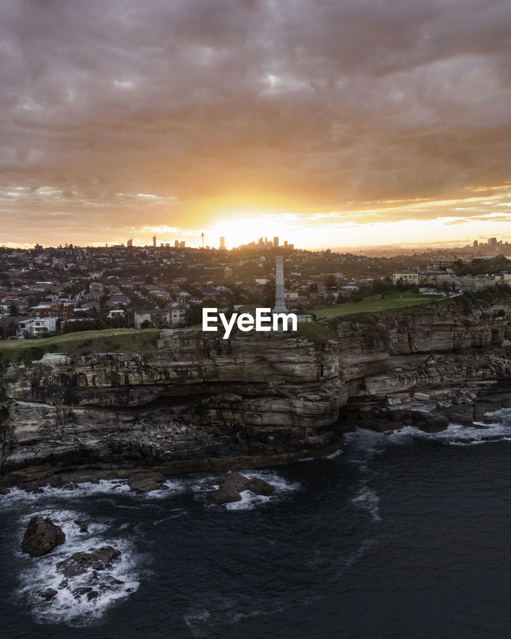 Scenic view of sea by buildings against sky during sunset