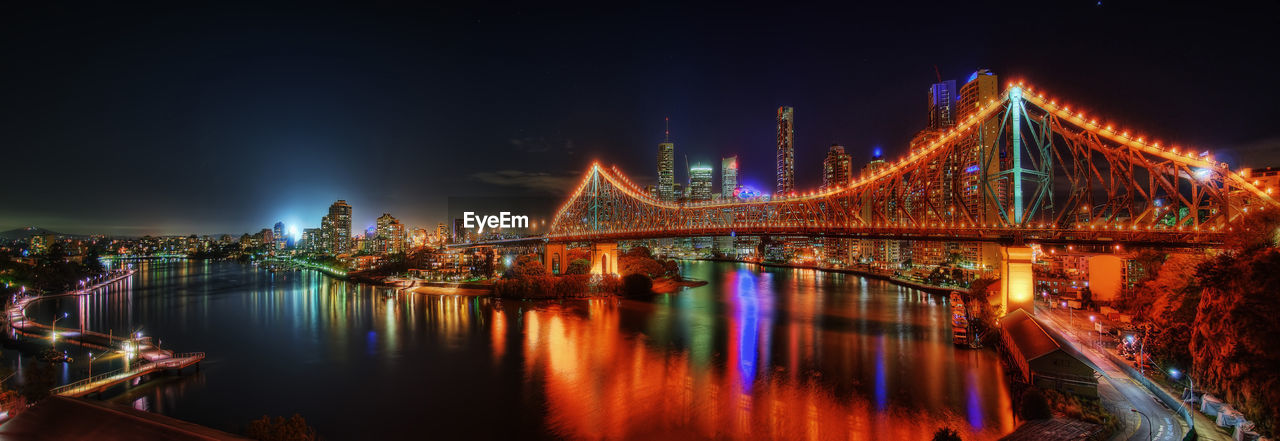 Illuminated bridge over river at night