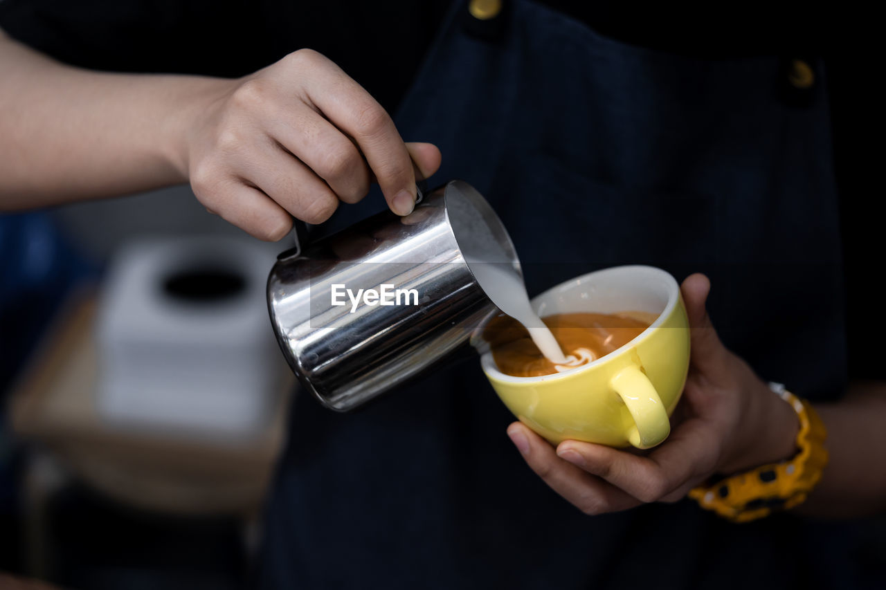 Midsection of man pouring coffee in cup