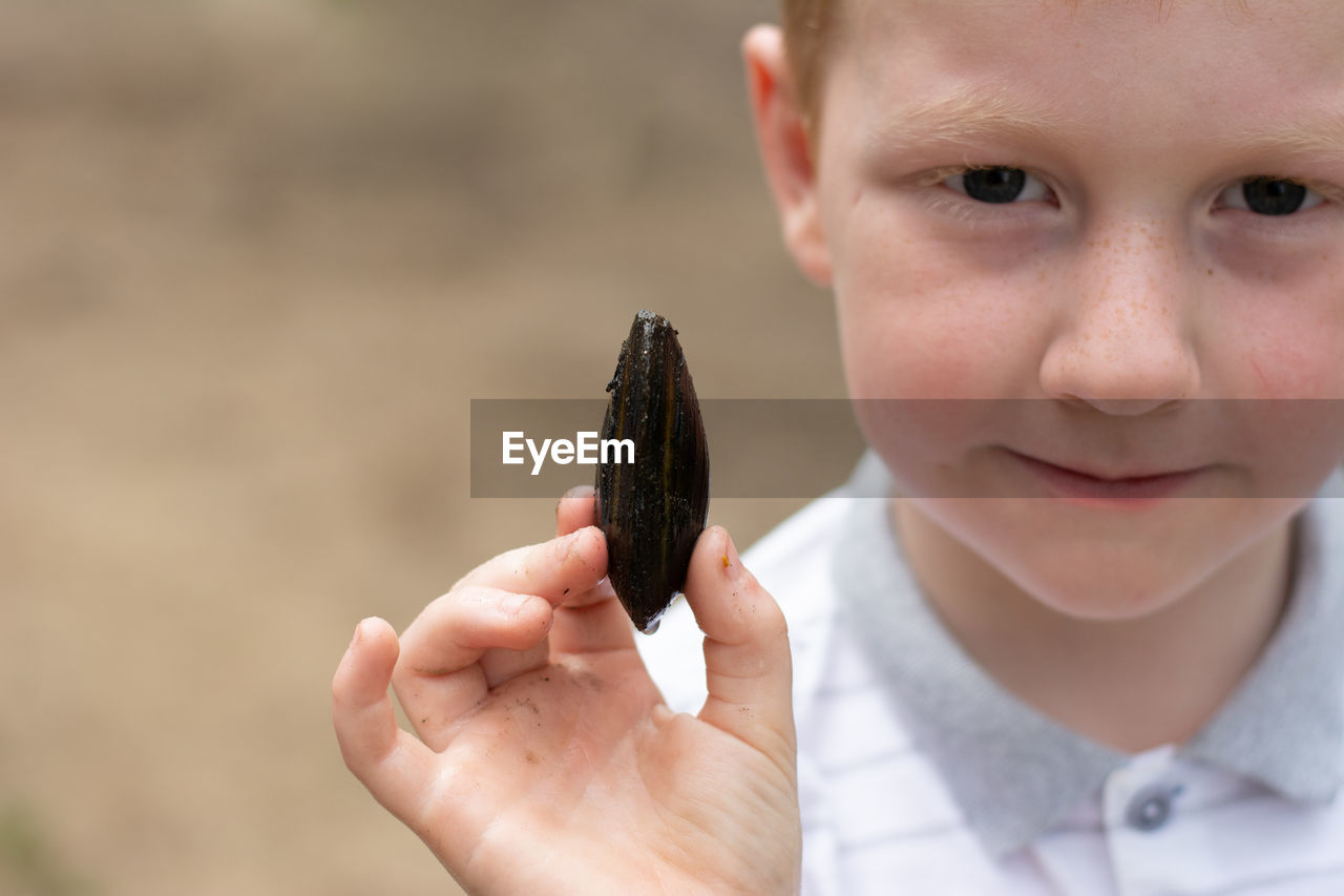 Close-up portrait of boy holding seashell