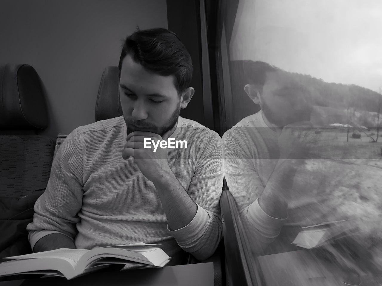 Man reading book while traveling in train