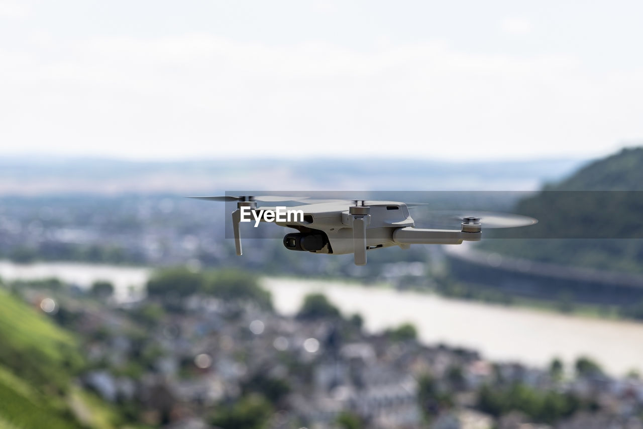 The drone hovers over the grape hills and countryside, the plastic propellers are on.