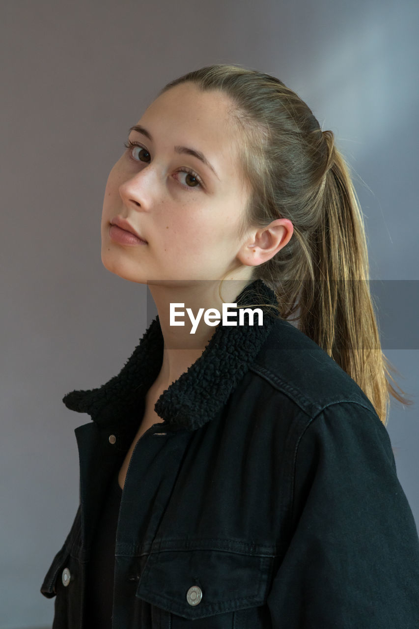 Portrait of young woman against gray background