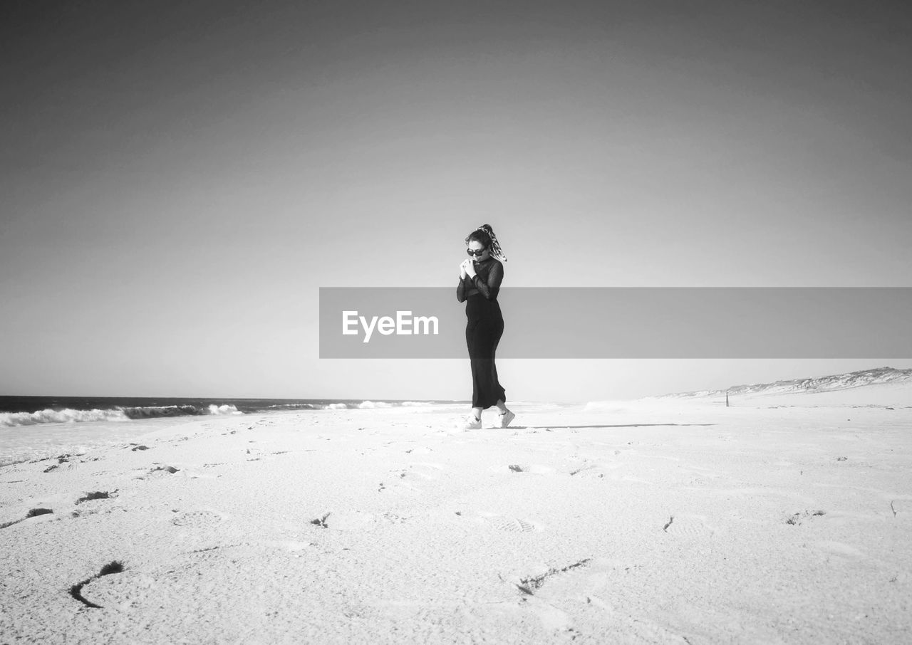 white, land, one person, black and white, full length, beach, sky, standing, sand, monochrome photography, adult, nature, monochrome, horizon, copy space, leisure activity, sea, holiday, vacation, solitude, trip, women, beauty in nature, clear sky, lifestyles, day, snow, scenics - nature, young adult, tranquility, water, black, horizon over water, outdoors, ocean, person, sunlight, travel, tranquil scene, environment, men