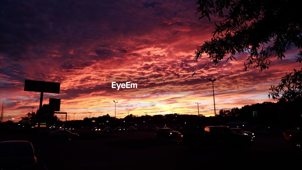 CARS ON STREET AGAINST DRAMATIC SKY