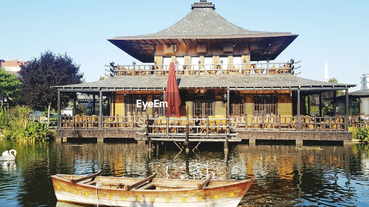 Traditional building by lake against sky