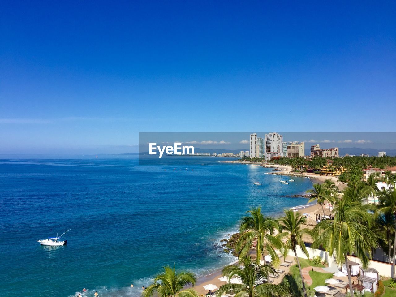 Scenic view of blue sea in city against clear sky