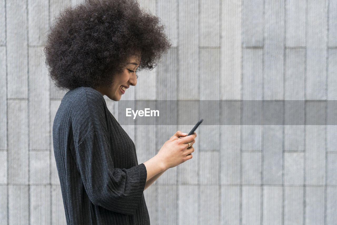 Happy young woman looking at smartphone