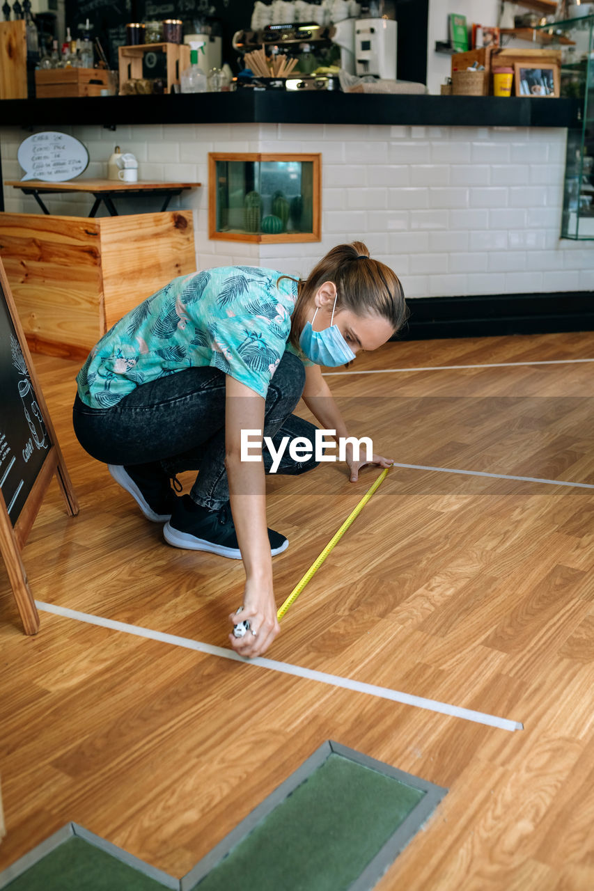 Full length of woman measuring floor