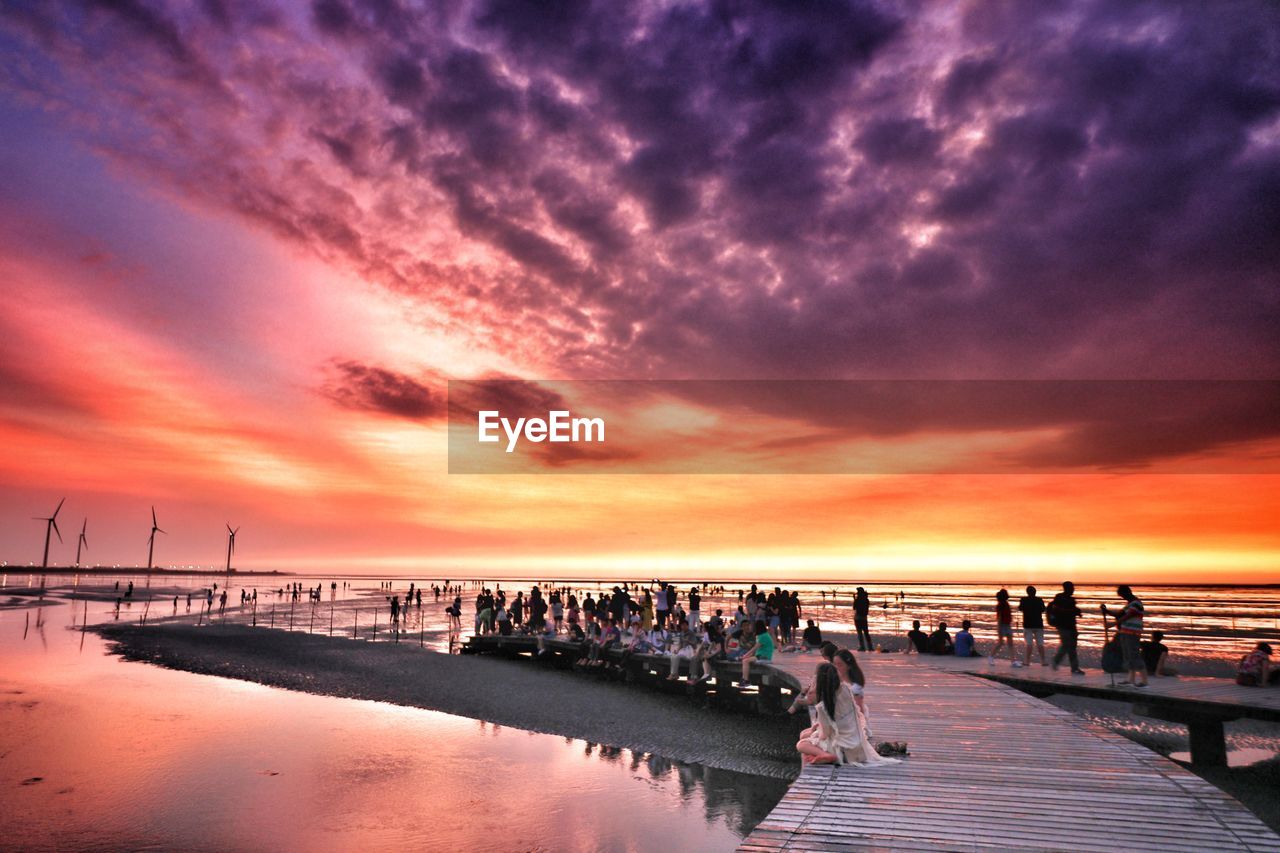 PEOPLE ON PIER AT BEACH DURING SUNSET