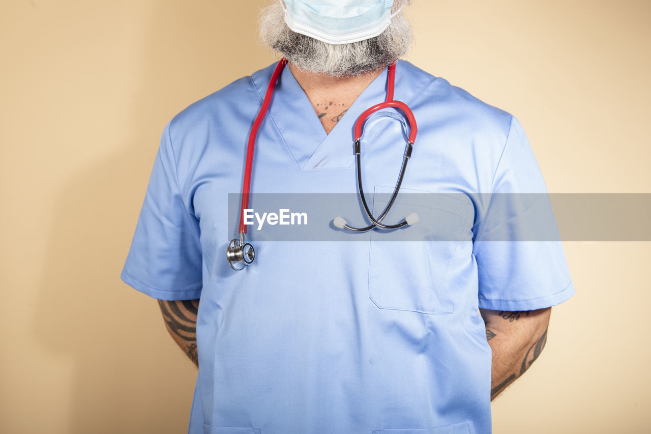 Close up of a male nurse wearing blue gown and mask isolated person