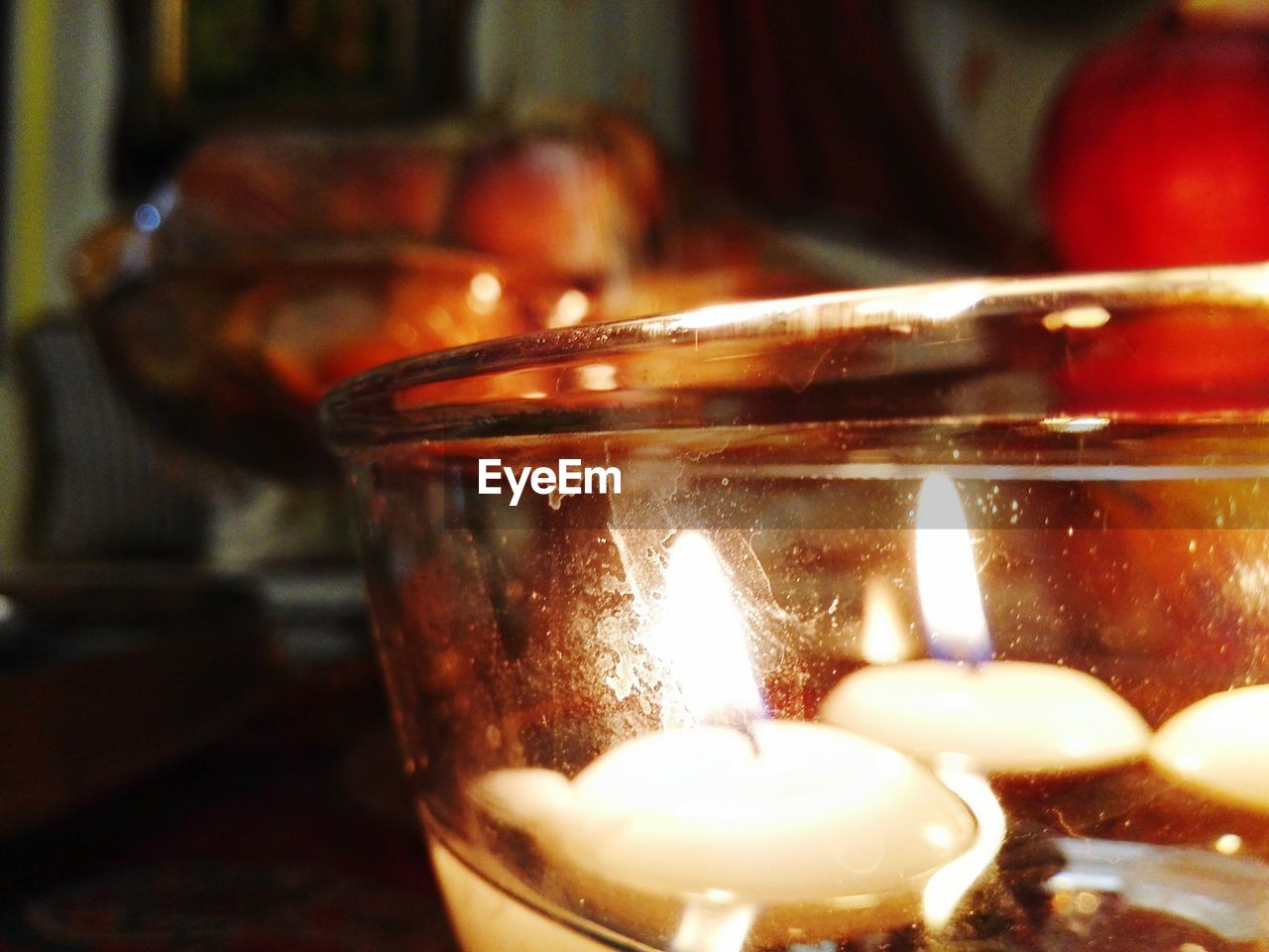 CLOSE-UP OF LIT CANDLE IN DARK ROOM