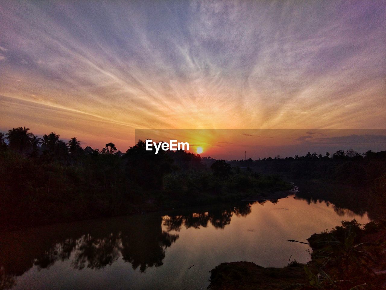 SCENIC VIEW OF LAKE BY SILHOUETTE TREES AGAINST ORANGE SKY