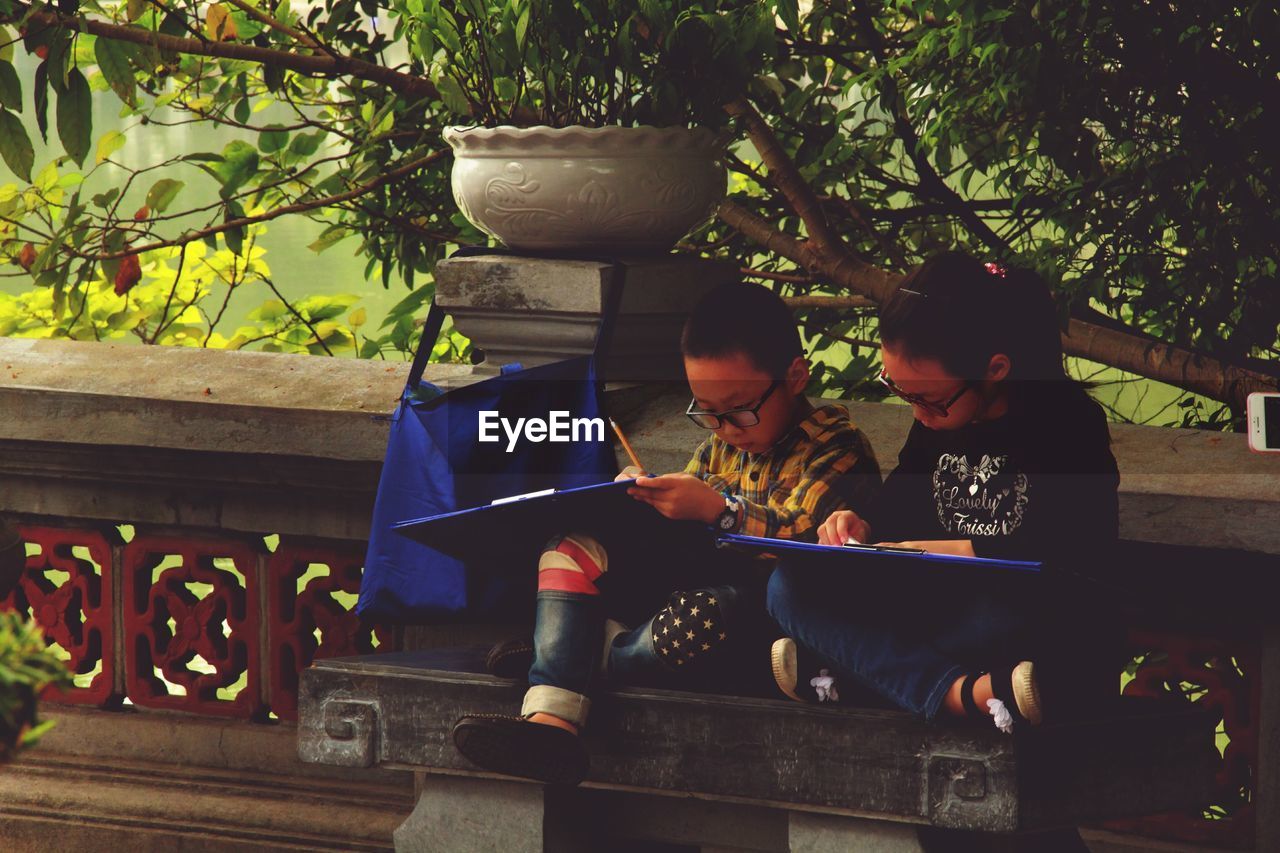 Children studying while sitting on bench