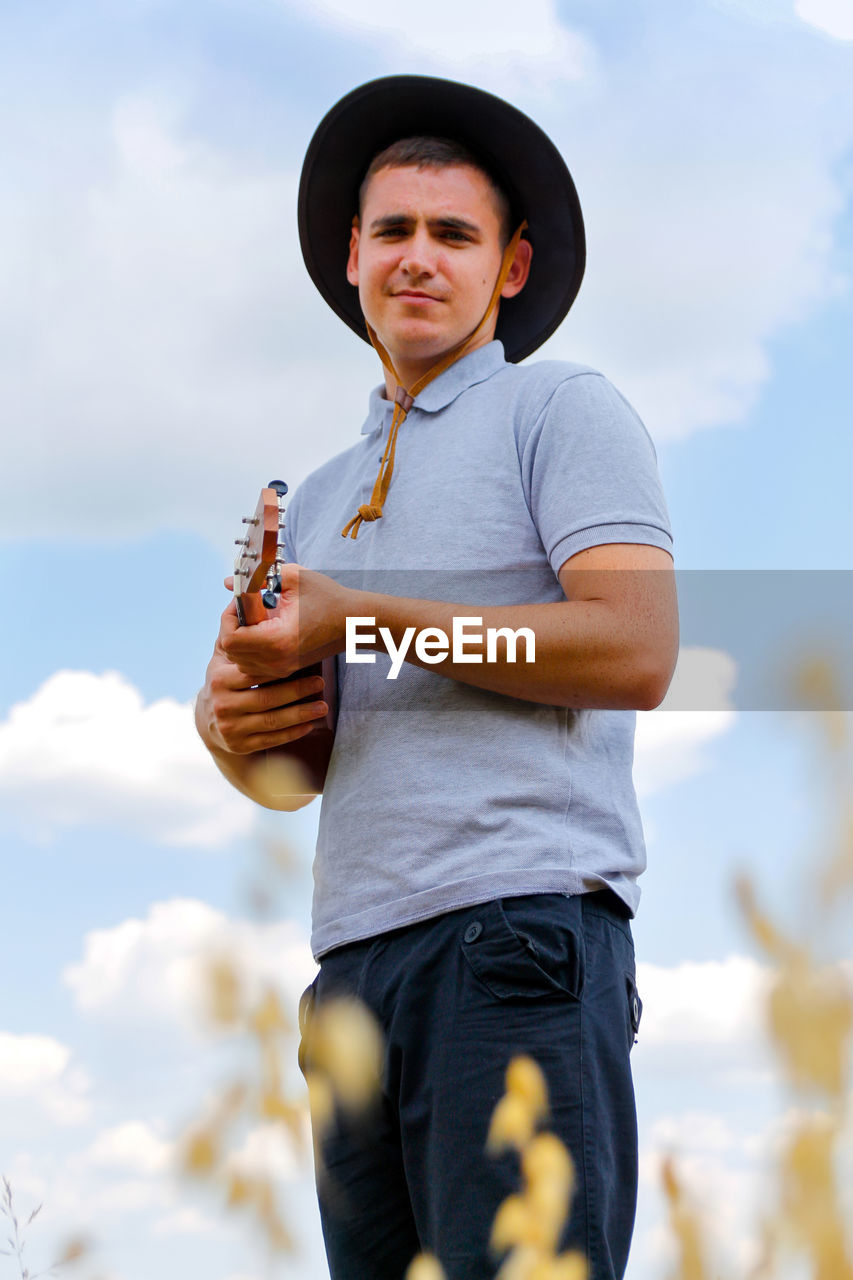 Lifestyle musician. young beautiful caucasian man playing ukulele outside. handsome hipster guy 