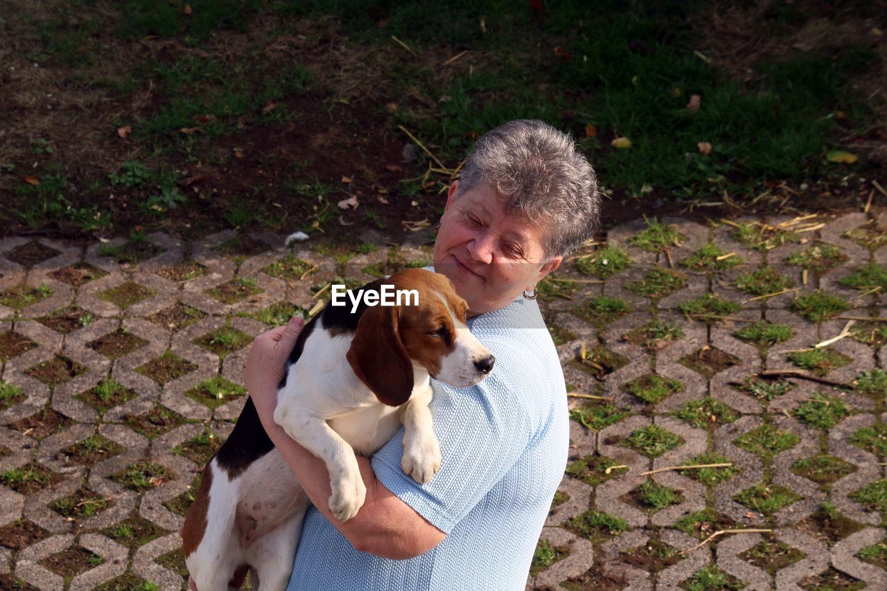 High angle view of woman holding dog on footpath