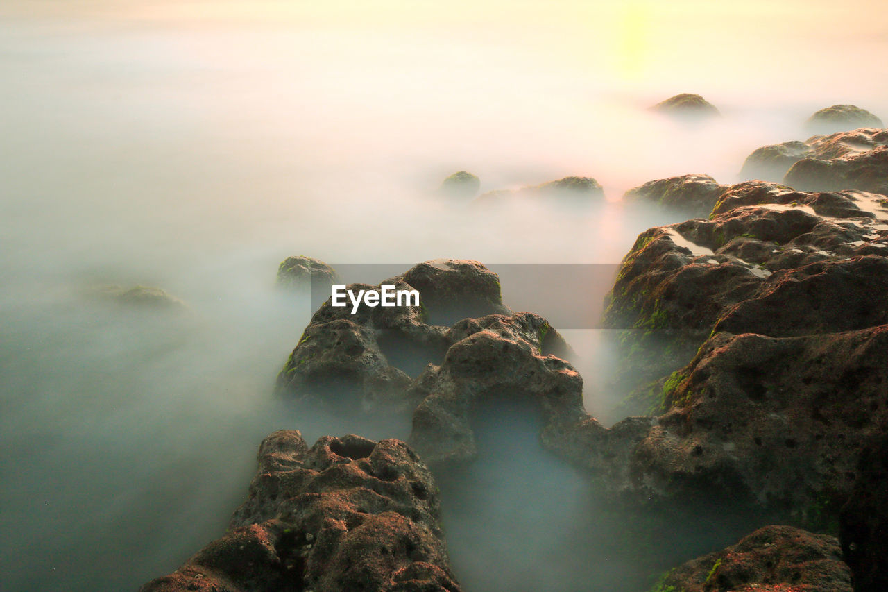 Scenic view of rocks in sea against sky during sunset