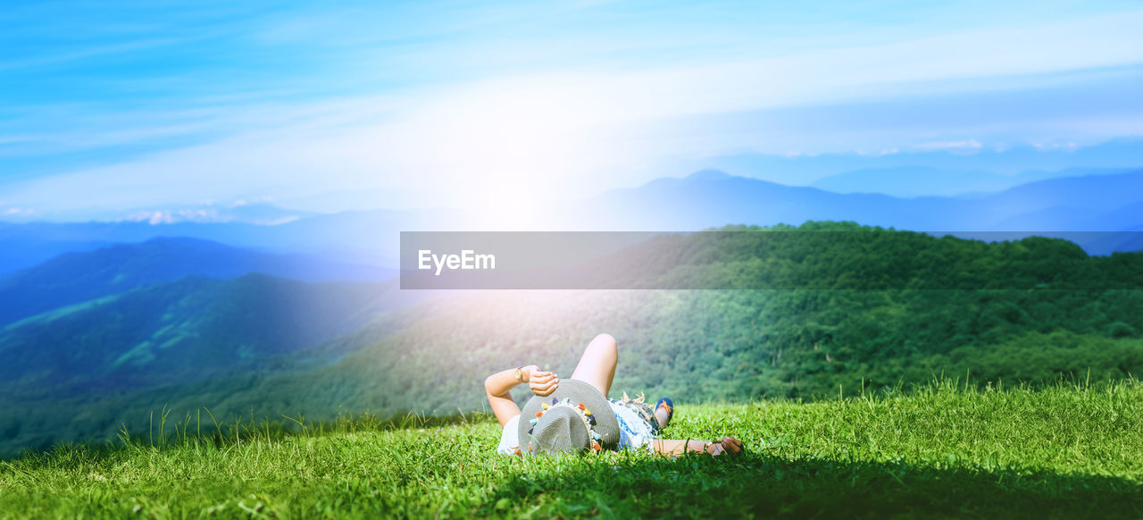 meadow, plant, grass, nature, sky, mountain, beauty in nature, environment, sunlight, landscape, scenics - nature, grassland, mountain range, green, land, field, tranquility, morning, sun, leisure activity, day, one person, tranquil scene, relaxation, horizon, idyllic, adult, outdoors, cloud, sitting, sunbeam, lens flare, non-urban scene, rural area, lifestyles, plain, women, summer, full length