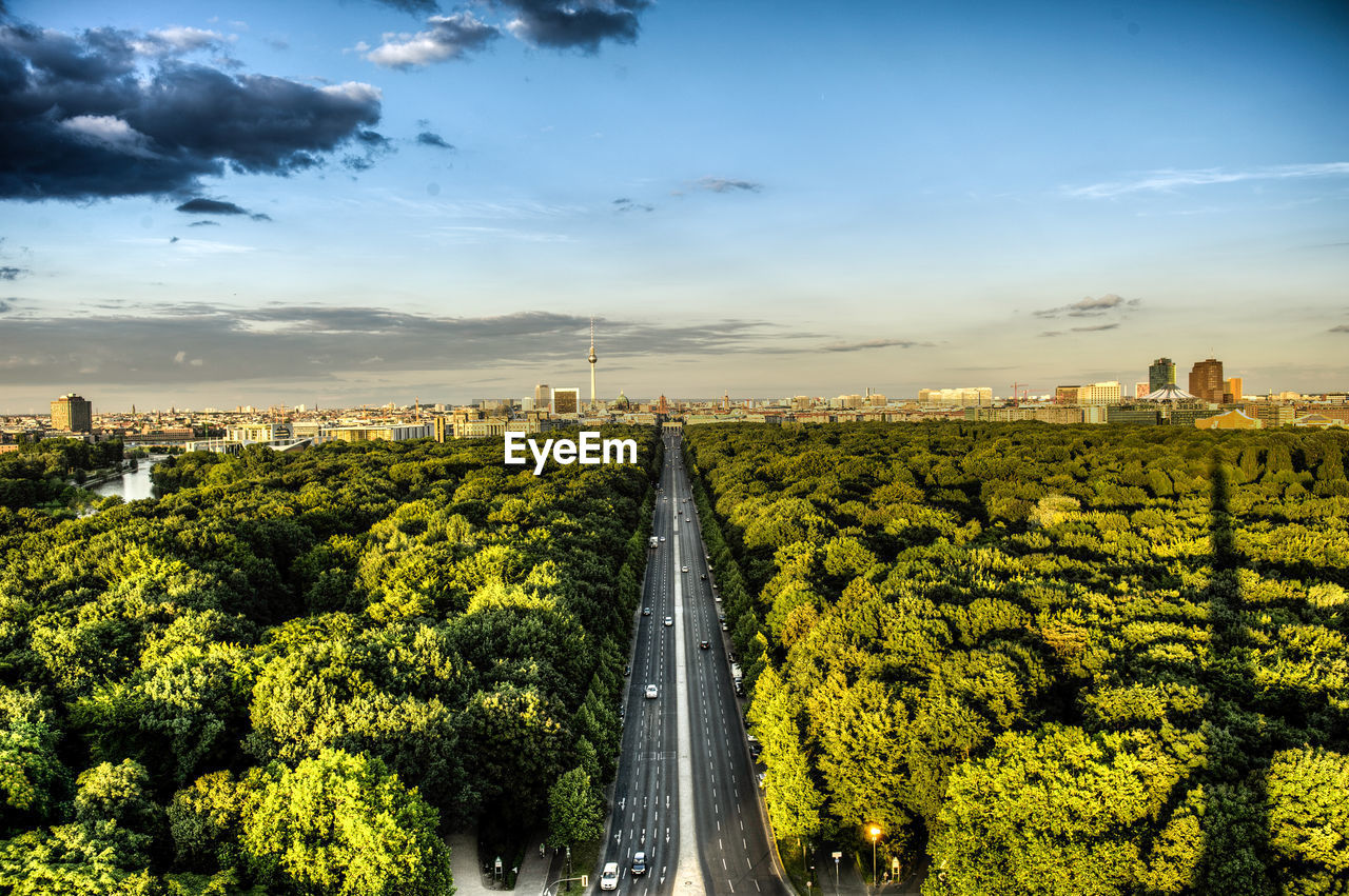 Aerial view of city street amidst trees against sky