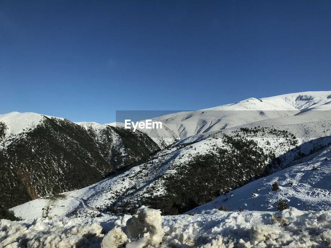 Scenic view of snowcapped mountains against clear blue sky