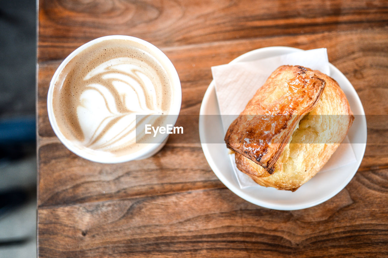 High angle view of cappuccino and baked pastry on table