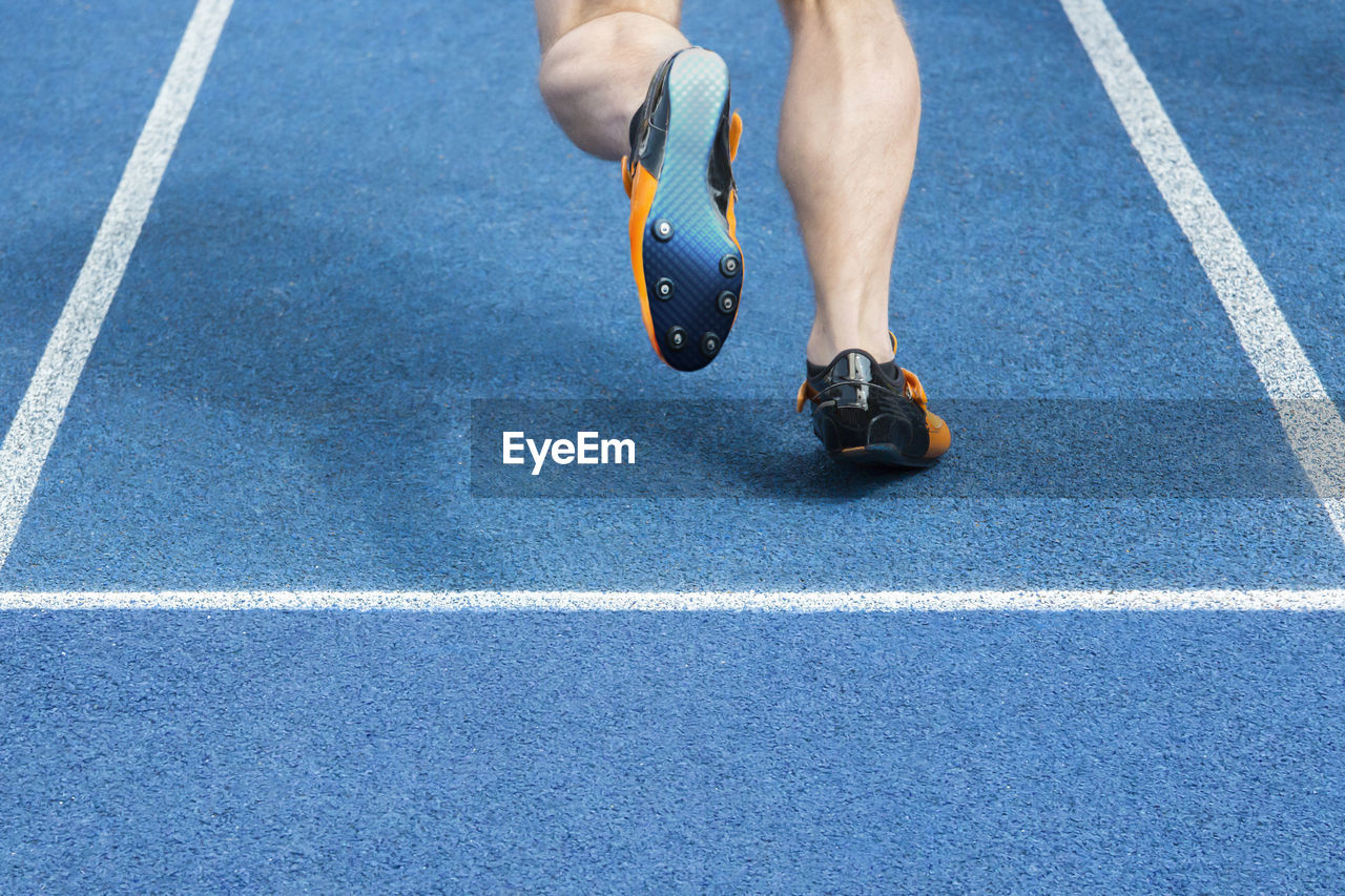 Low section of male athlete running on track