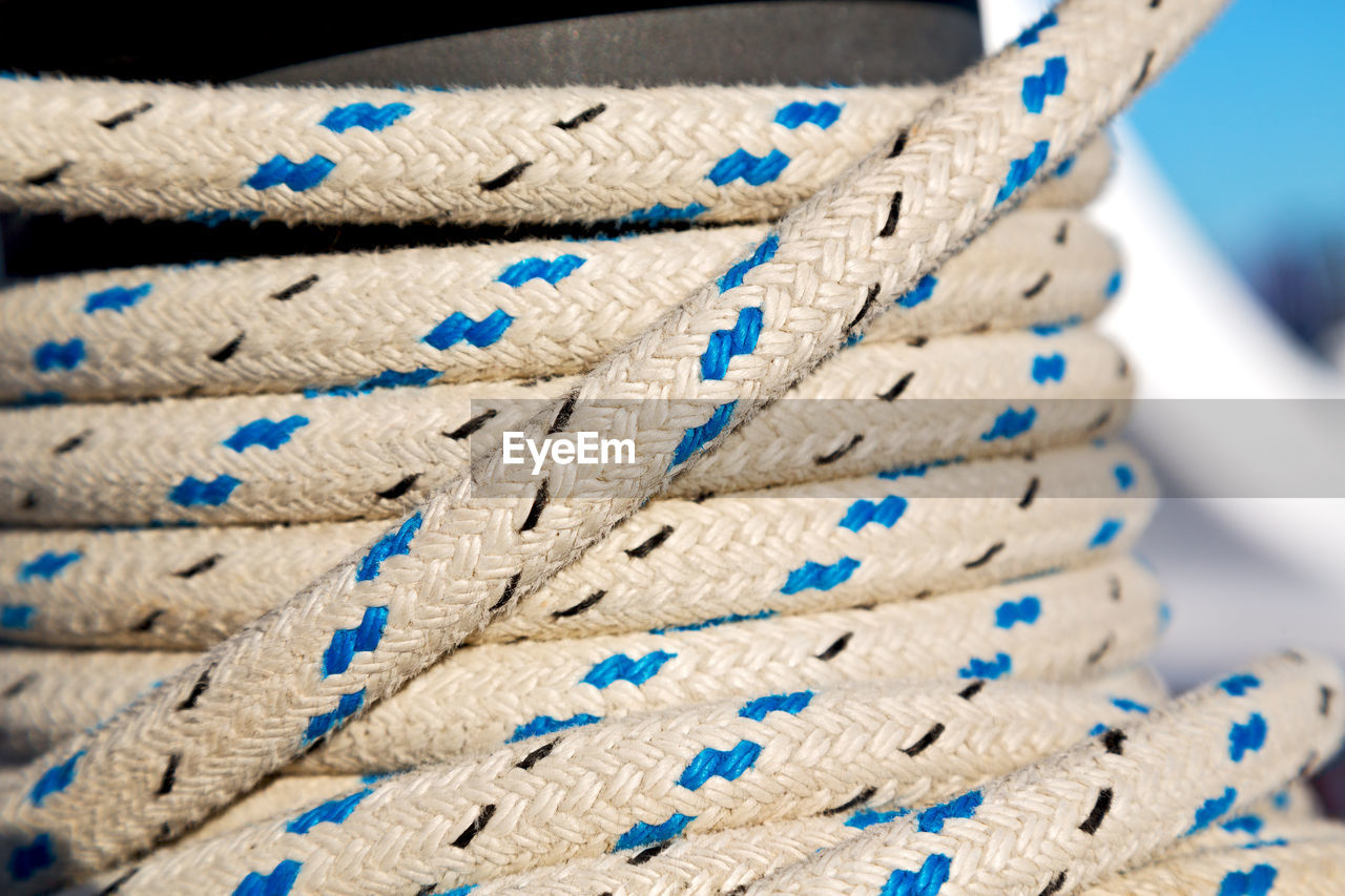 CLOSE-UP OF ROPE TIED ON STACK OF BLUE