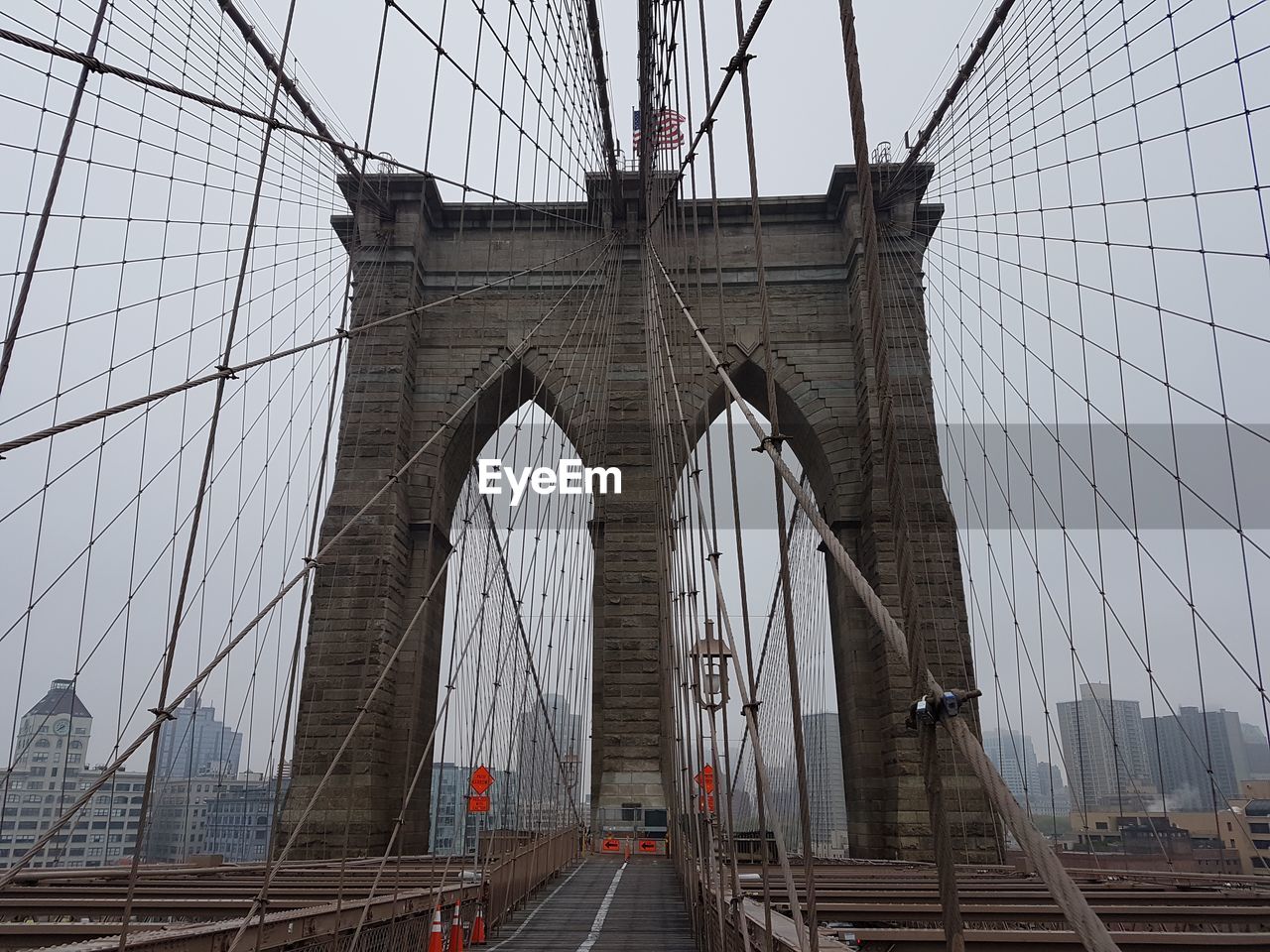 Low angle view of brooklyn bridge against sky during foggy weather