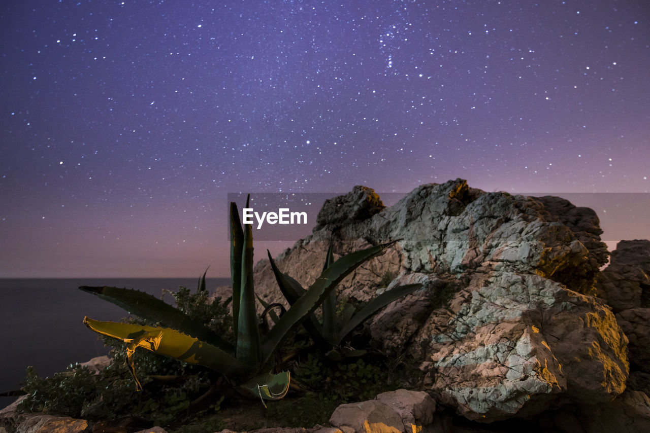 SCENIC VIEW OF MOUNTAIN AGAINST STAR FIELD AT NIGHT