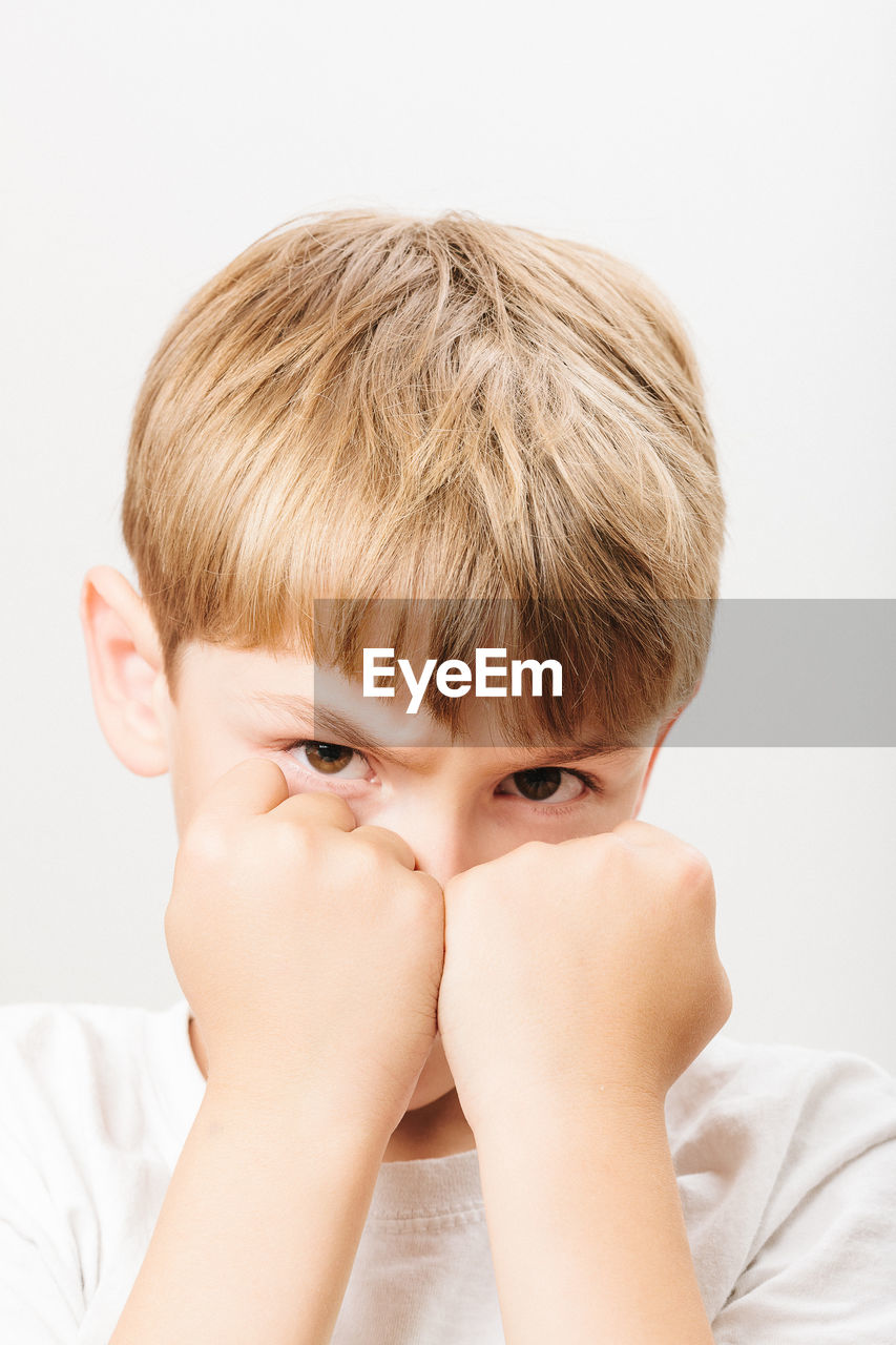 Boy showing fist over white background