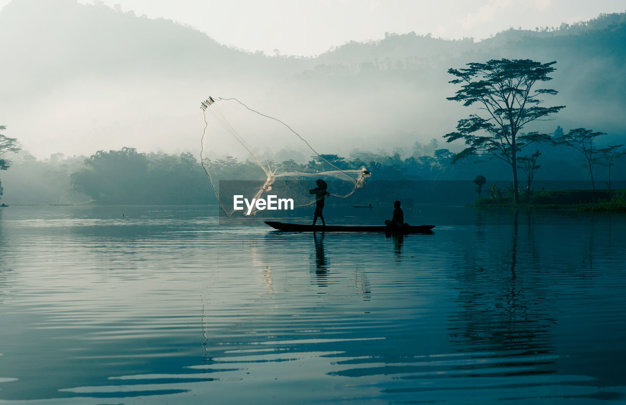 Silhouette fisherman fishing in lake