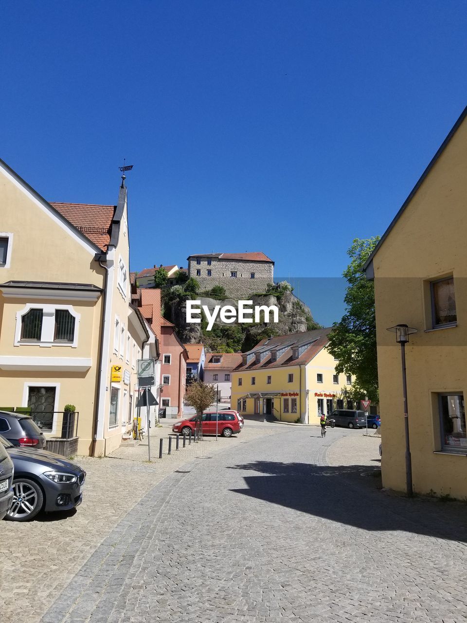 CARS ON ROAD BY BUILDINGS AGAINST BLUE SKY