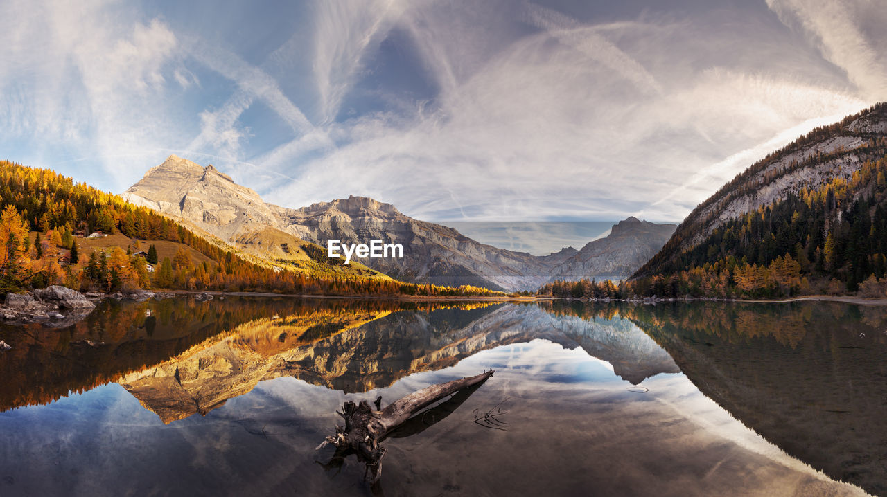 Spectacular scenery of lake with smooth surface reflecting amazing mountain range and sky